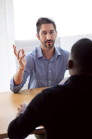 Tell me about your previous work experience. a businessman interviewing a job applicant in an...
