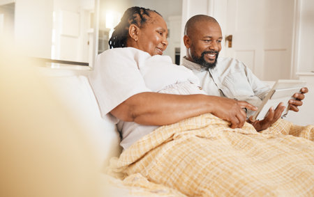 Memory, photo album and love with a black couple sitting on a sofa in the living room of their home together. Nostalgia, retirement or relax with a senior man and woman looking at photographsの写真素材