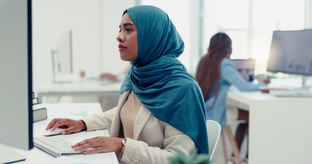 Muslim, business woman and typing on computer in office, startup company and digital management, internet planning and strategy review. Employee with islamic hijab working online for seo website techの写真素材