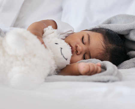 Sleeping, teddy bear and cute with baby in bedroom for relax, comfortable and dreaming. Innocence, young and rest with tired child at home for and napping with toy for bedtime, youth and sweetの写真素材