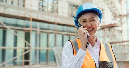 Engineering, construction site and woman in communication on a walkie talkie building a development project outside. Smile, contractor and happy senior manager talking or speaking on safety on radioの写真素材