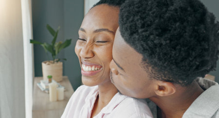 Morning, window and couple hug in bedroom for cute embrace with warm beverage and cheek kiss. Bond, intimacy and care in relationship with black people who love living together in apartment.の写真素材