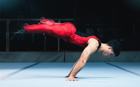 Gymnast, handstand and man on gym floor for training, balance and wellness with muscle, strong body and night. Gymnastics, athlete and exercise in studio for competition, goals and fitness for sportの写真素材