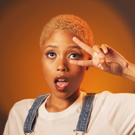 Peace sign, surprise and black woman with success, casual outfit and brown studio background. African American female, lady and expression with hand gesture, wow and fashion with emoji and motivationの写真素材