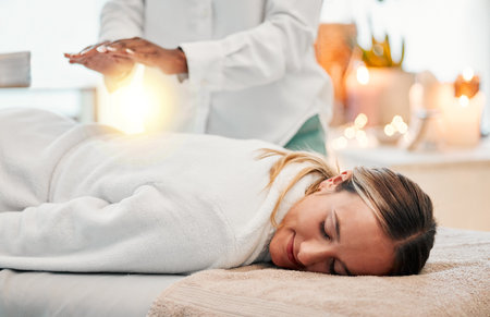 Relax, reiki and woman on bed at spa for chakra therapy with light energy and holistic medicine. Spiritual healing, balance and zen, person with peaceful and healthy mindset at traditional massage.の写真素材