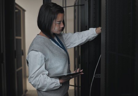 Tablet, server room and engineering with a programmer asian woman at work on a computer mainframe....