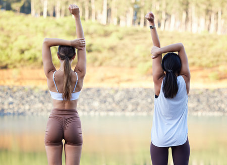 Exercise, stretching and women outdoor in nature for fitness, peace and wellness. Young friends or people warm up at forest lake for workout, training and energy for mental health, chakra and zenの写真素材