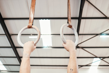 Hands, rings and gymnastics in fitness for workout, strength training or practice at gym. Hand of athlete, gymnast or acrobat holding or hanging on ring circles for strong intense pull up exerciseの写真素材