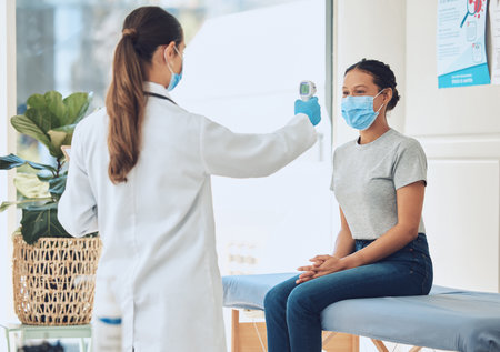 Healthcare, compliance and covid scan by doctor and patient with digital thermometer in a consultation room. Healthcare worker checking for fever and corona symptoms, practice safety during pandemicの写真素材