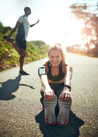 Preparing her muscles for an amazing workout. Shot of a young woman stretching before her run outdoors.の写真素材