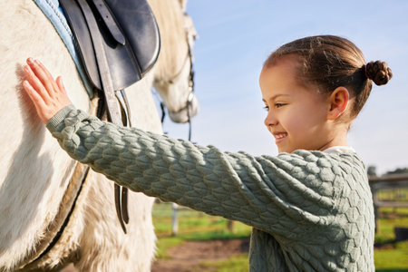 A young rider and her horse. Cropped shot of an adorable young girl petting her horse outside on the ranch.の写真素材
