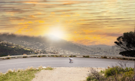 Road, view and sunset with a skater man moving at speed on an asphalt street for sports in nature. Aerial, motion blur or skating and a male athlete outdoor to balance on a board to skate fastの写真素材
