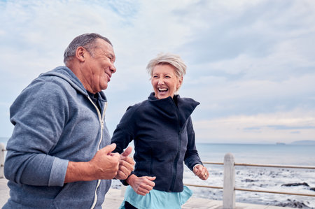 Running, fitness and senior couple laugh by ocean for exercise, healthy body and wellness in retirement. Sports, marriage and happy elderly man and woman for smile, cardio workout and training by seaの写真素材