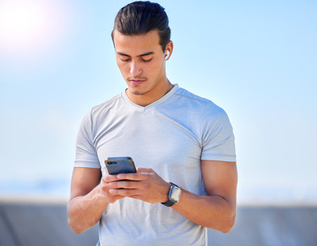 Phone, fitness and man texting on social media or streaming music online during morning exercise or workout routine. Person, web and athlete using a mobile training app or website to track healthの写真素材