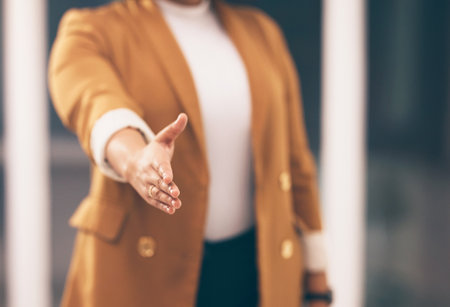Professional woman with a handshake gesture for greeting, welcome or partnership in office. Company, corporate and female employee stretching hand for shaking hands for agreement in modern workplace.の写真素材