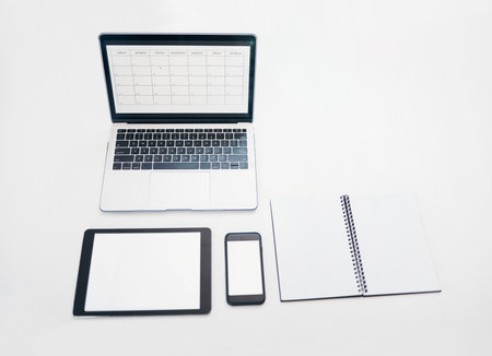 Laptop, tablet and phone mockup with notebook above for schedule planning, advertising or marketing. Computer, touchscreen and smartphone screen display for calendar reminder or organized workspaceの写真素材