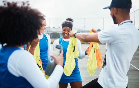 Coach, vest or team in netball training game, workout or exercise for a match on sports court. Teamwork, fitness group or manager giving bibs to excited athlete girls with happy smile in practiceの写真素材