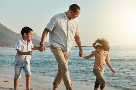 Holding hands, children and grandfather walking on beach, having fun or bonding outdoors. Love, care and happy grandpa with kids, boy and girl by ocean or seashore enjoying holiday vacation at sunsetの写真素材