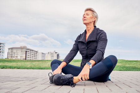 Woman, breathing and stretching exercise at park, sky mockup and ground for training in Miami. Senior female, breathe and fitness outdoor for workout, sports and meditation for healthy runner mindsetの写真素材