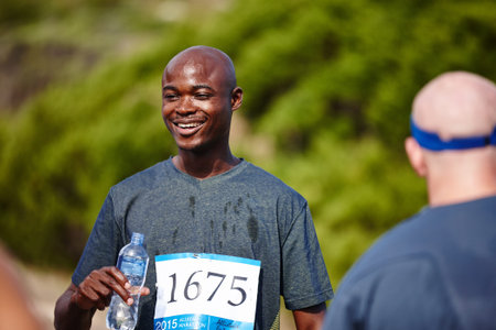 Taking an H2O time out. a young male runner drinking water after a race.