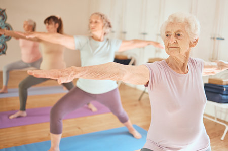 Exercise, yoga and group of senior women in gym training for fitness, healthcare and wellness. Pilates, meditation and retired females stretching arms in fitness center for balance workout together.の写真素材
