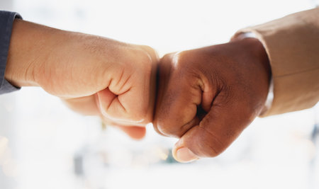 Business people, hands and fist bump in partnership, unity or trust for deal or agreement against blurred background. Hand of team bumping fists in collaboration, teamwork or goals in support for winの写真素材