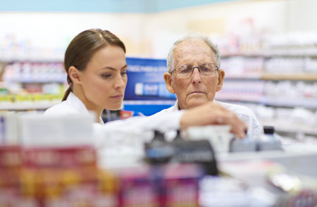Helping her customer make an informed choice. a young pharmacist helping an elderly customer.の写真素材