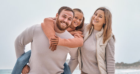 Happy family, beach vacation and summer travel with child, mom and dad together on adventure by sea with love, support and fun piggy back. Portrait of man, woman and girl outdoor by water for holidayの写真素材