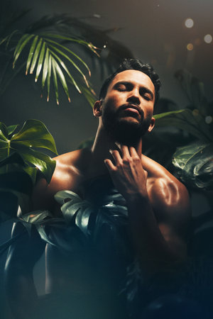 Beauty, skincare and nature with a man model in studio on a natural rainforest or amazon background. Cosmetics, wellness and plants with a handsome young male posing indoors on a jungle settingの写真素材