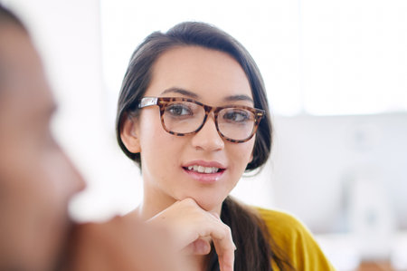 Listening intently. Portrait of an attractive young woman sitting in a meeting with coworkers.の写真素材