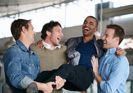 He makes them proud. a group of male coworkers celebrating in an office.の写真素材