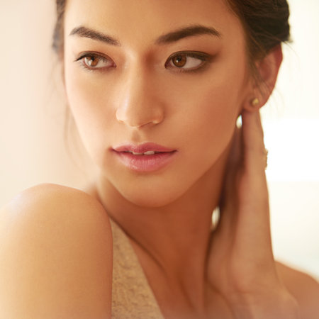 Striking beauty. Closeup shot of a beautiful young woman dressed elegantly in gold.の写真素材
