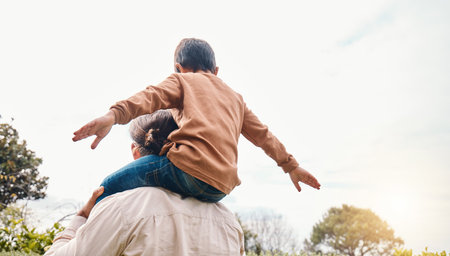 Playing, nature and a father carrying a child for adventure, bonding and quality time. Freedom, love and back of a dad with a boy kid for a walk, vacation or free in a park or garden togetherの写真素材