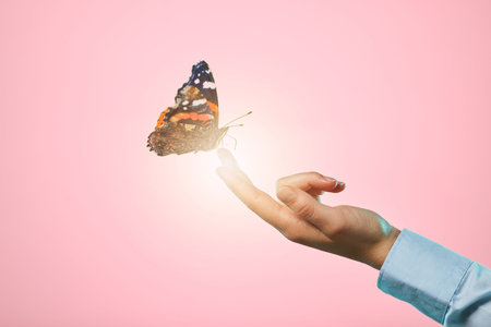 Butterfly, studio and hand with insect and lens flare in isolated pink background. Bright, bug and woman hands with nature and spring aesthetic with light glow and bugs with advertisement spaceの写真素材
