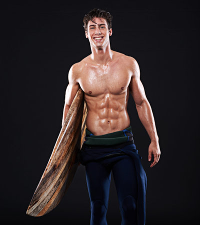Hes a sensation in the surf. Studio portrait of a young surfer with a vintage board.
