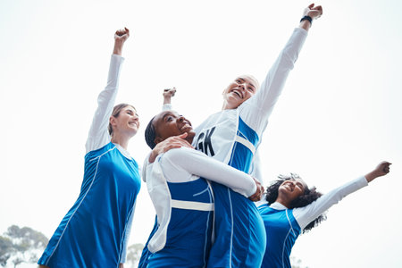 Women, friends and celebration for winning, sports team or success raising fist together in the outdoors. Happy sporty woman group smiling in sport teamwork celebrating win, victory or achievementの写真素材