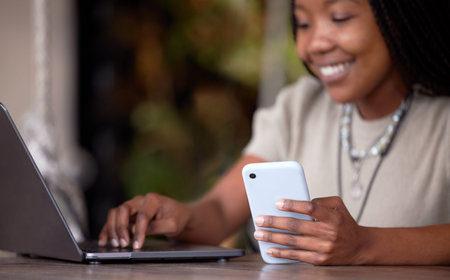 Black woman, phone and laptop at cafe for communication, social media or chatting in remote work....