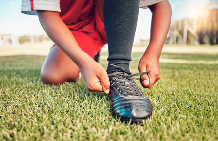 Sports, football field and child tie shoes for match workout, challenge contest or practice exercise...