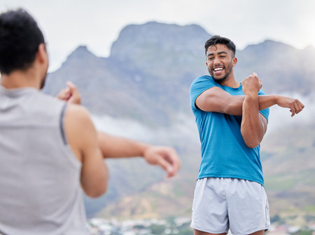 Stretching, fitness and friends ready for running on a mountain, training and marathon in nature. Health, happy and athlete men with a warm up before exercise, sports and workout in the mountainsの写真素材