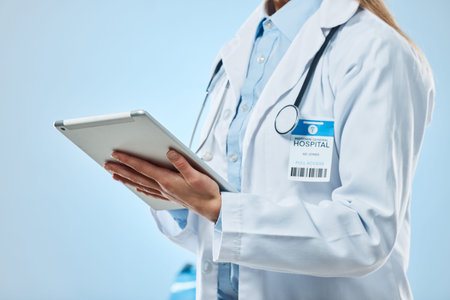 Doctor hands, tablet and medical technology for a hospital or clinic in a studio. Isolated, blue...