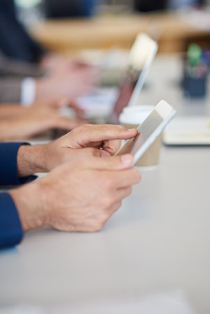 Total touchscreen technology. a group of business professionals sitting around the table in a meeting while using modern technology.の写真素材