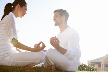 Enjoying their time of meditation together. Full length shot of a young couple doing yoga outdoors.の写真素材