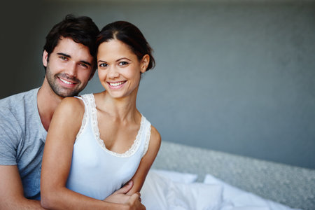 The face of newly-weds. Portrait of a happy couple sitting on their bed with copyspace.の写真素材
