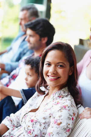 Enjoying a day spent with her family. A smiling young woman looking at the camera while sitting with her family.の写真素材