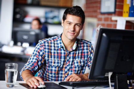 Hes your man if you want the job done well. Portrait of a handsome young designer sitting at his desk in the office.の写真素材