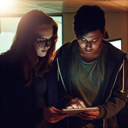 Planning, tablet and research with people in office at night for teamwork, web design and strategy. Creative, collaboration and technology with man and woman in startup for data, proposal and ideaの写真素材