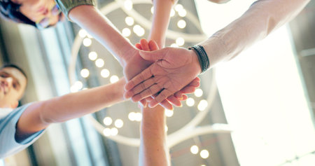 Teamwork, collaboration and low angle of business people with hands together in office. Team building, solidarity and group of employees huddle for unity, union and motivation, goals and targets.の写真素材
