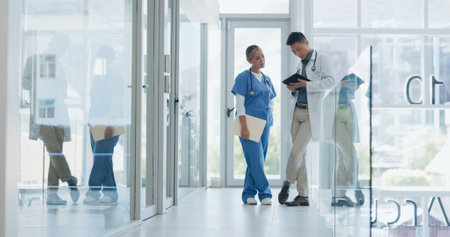 Healthcare, nurse and doctor talking, walking in lobby and consultation for advice, diagnosis and tablet. Medical professionals, Asian man and woman in hospital, update charts or planning for surgeryの写真素材