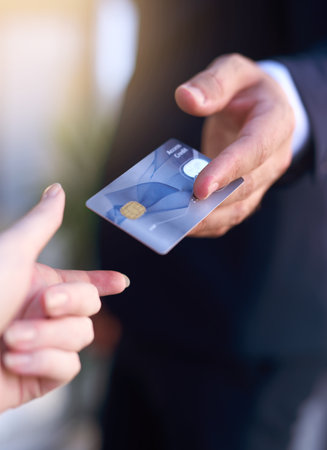 Paying by card. Cropped shot of a businessman holding out a credit card as payment.の写真素材