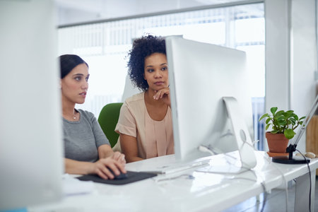 On the right track to success. two creative businesspeople working together on a computer in the office.の写真素材